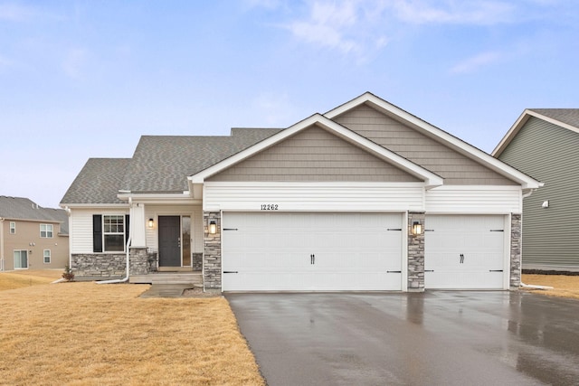 view of front of home featuring aphalt driveway, stone siding, roof with shingles, and an attached garage