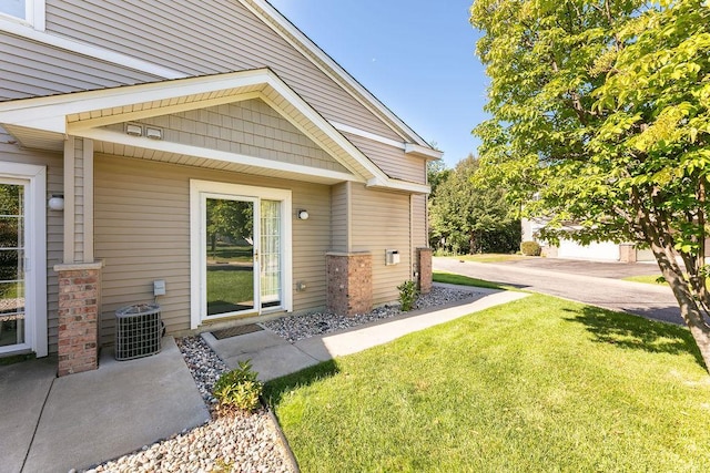 view of exterior entry featuring a yard and central AC