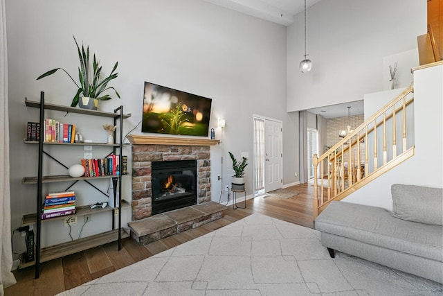 living room featuring baseboards, a fireplace, wood finished floors, and stairs