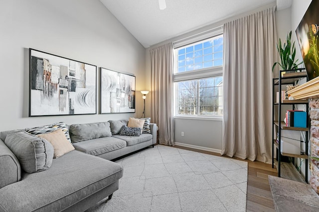 living area featuring high vaulted ceiling, baseboards, and wood finished floors