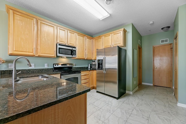 kitchen with visible vents, a sink, light brown cabinetry, stainless steel appliances, and marble finish floor