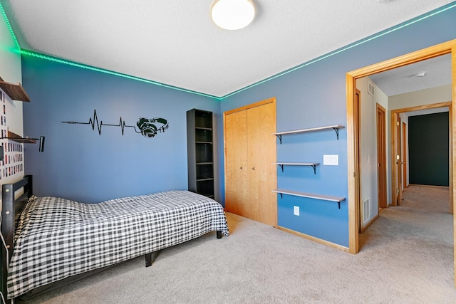 carpeted bedroom with visible vents, baseboards, a textured ceiling, and a closet