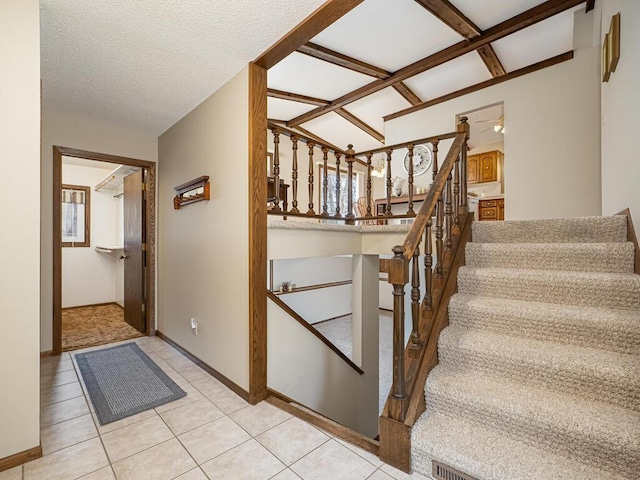 stairs with tile patterned flooring, vaulted ceiling, a textured ceiling, and baseboards