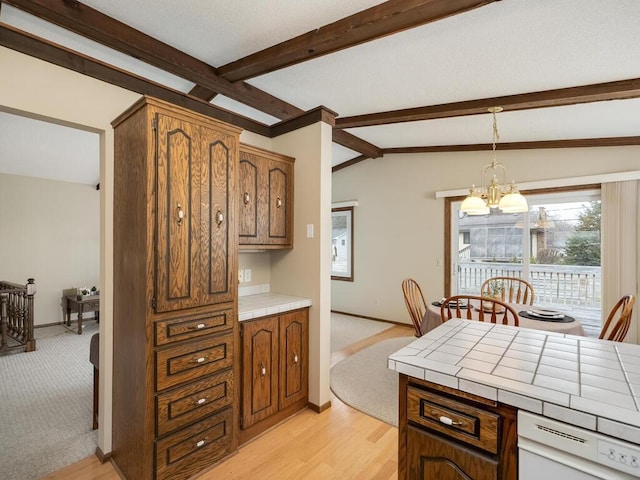 kitchen featuring tile counters, brown cabinetry, vaulted ceiling with beams, pendant lighting, and a notable chandelier