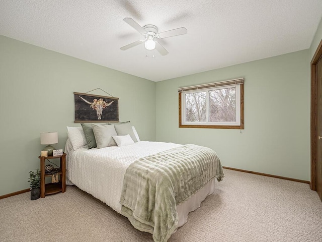 bedroom featuring a ceiling fan, light carpet, a textured ceiling, and baseboards