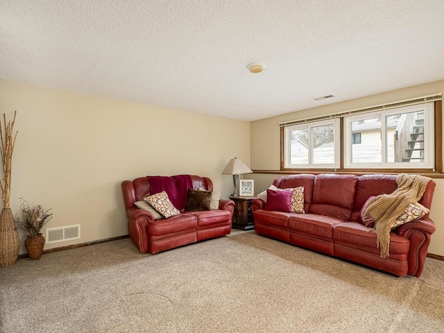 carpeted living area with visible vents, a textured ceiling, and baseboards