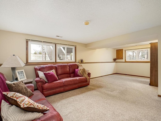 carpeted living area featuring visible vents, baseboards, and a textured ceiling