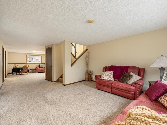 living area with a textured ceiling, stairs, baseboards, and carpet flooring