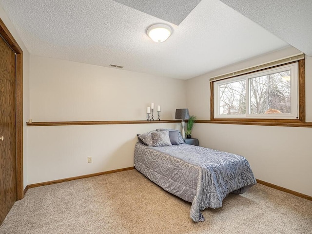 bedroom with carpet, a textured ceiling, visible vents, and baseboards