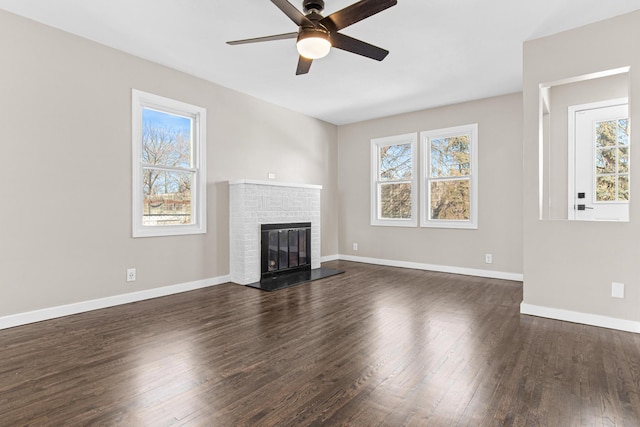 unfurnished living room featuring ceiling fan, a fireplace, baseboards, and dark wood-style flooring