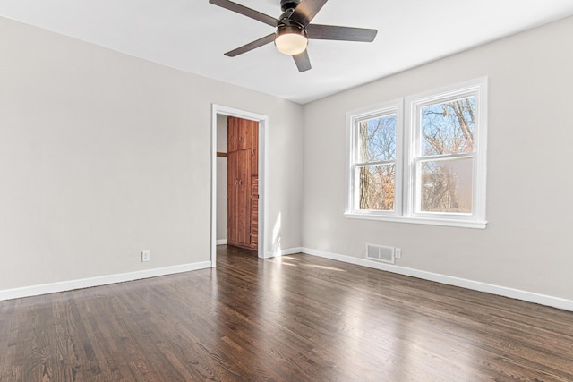 spare room featuring visible vents, baseboards, dark wood-type flooring, and a ceiling fan