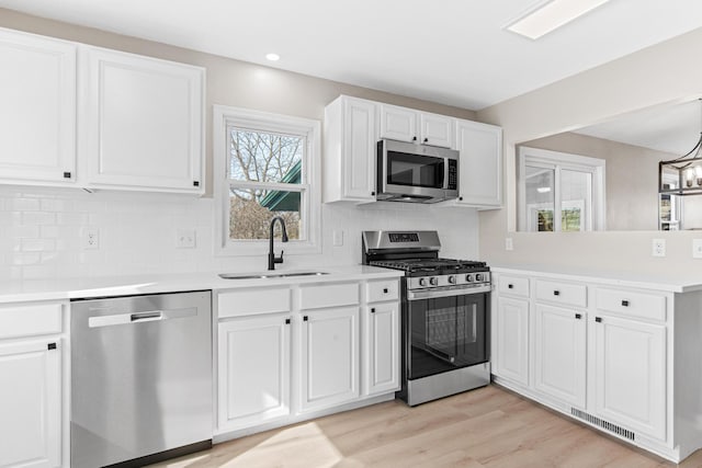 kitchen with visible vents, a sink, white cabinetry, appliances with stainless steel finishes, and a peninsula