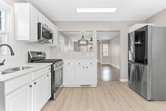 kitchen with a sink, light countertops, appliances with stainless steel finishes, tasteful backsplash, and light wood-type flooring