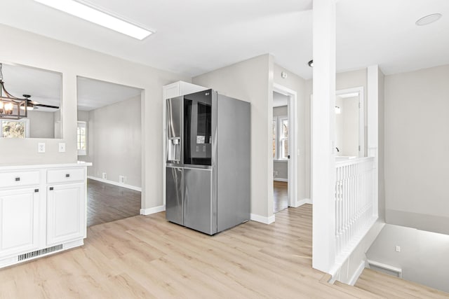 kitchen featuring visible vents, stainless steel fridge, light wood-style flooring, and white cabinetry