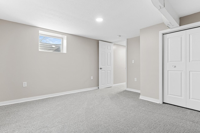 below grade area featuring carpet flooring, baseboards, and a textured ceiling