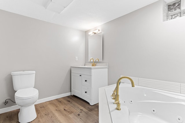 bathroom featuring baseboards, toilet, wood finished floors, a tub with jets, and vanity