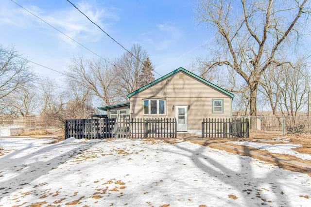 snow covered back of property with a wooden deck and fence