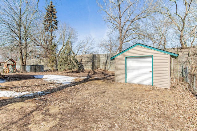 exterior space featuring driveway, a shed, a fenced backyard, an outdoor structure, and a garage