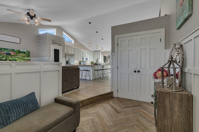 kitchen featuring light countertops, appliances with stainless steel finishes, open floor plan, high vaulted ceiling, and a kitchen bar