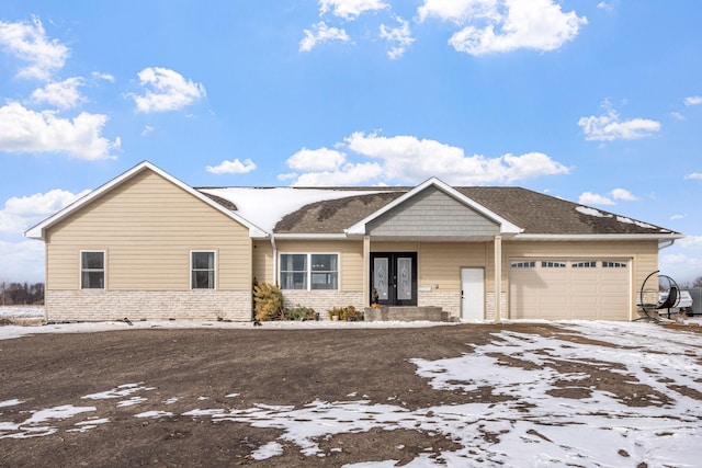 view of front of property with an attached garage, french doors, and brick siding