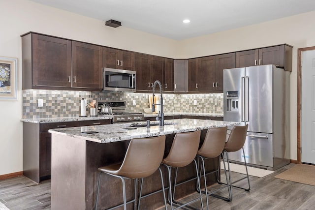 kitchen with dark brown cabinetry, light wood-style flooring, and appliances with stainless steel finishes