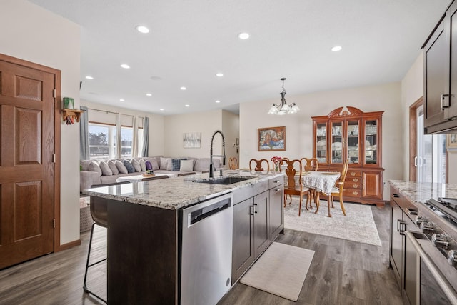 kitchen with a sink, a notable chandelier, appliances with stainless steel finishes, and dark wood-style flooring