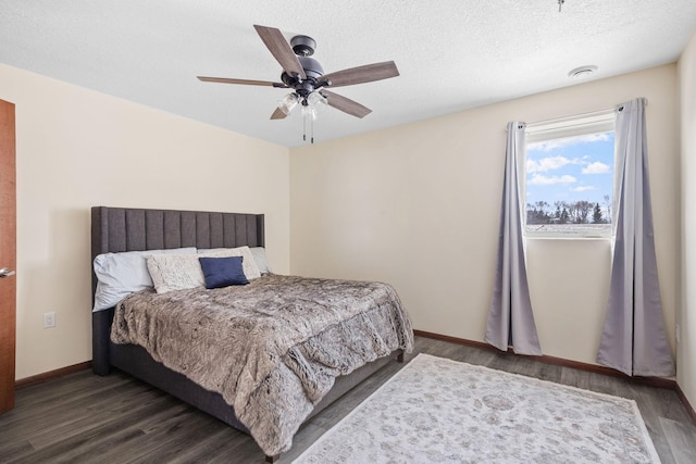 bedroom with a ceiling fan, wood finished floors, baseboards, and a textured ceiling