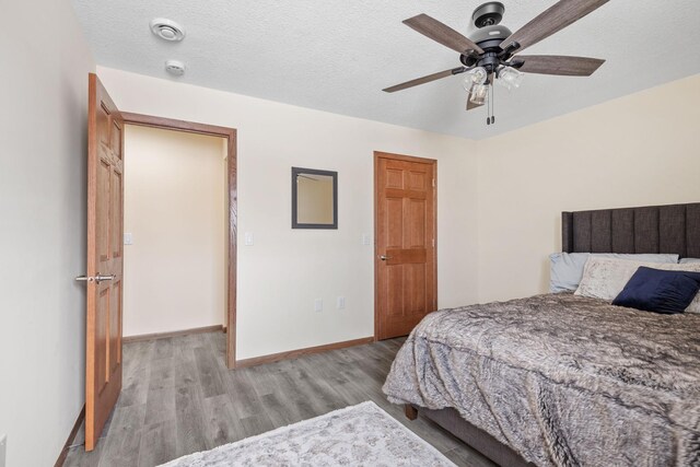 bedroom with a ceiling fan, baseboards, light wood finished floors, and a textured ceiling