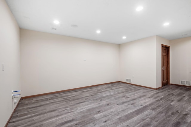 empty room with recessed lighting, wood finished floors, visible vents, and baseboards