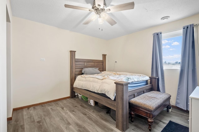 bedroom featuring baseboards, light wood-style floors, ceiling fan, and a textured ceiling