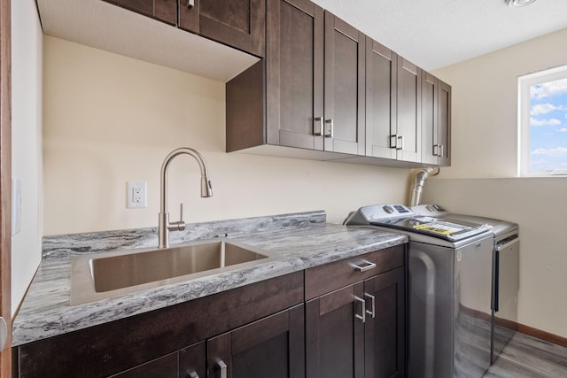 laundry area with baseboards, washer and clothes dryer, wood finished floors, cabinet space, and a sink