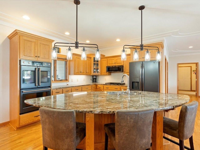 kitchen with a sink, double wall oven, ornamental molding, and black fridge