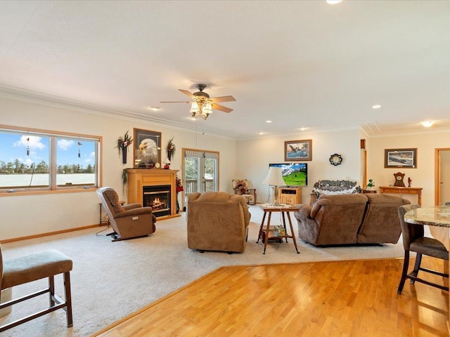 living room with crown molding, baseboards, light wood finished floors, and a lit fireplace