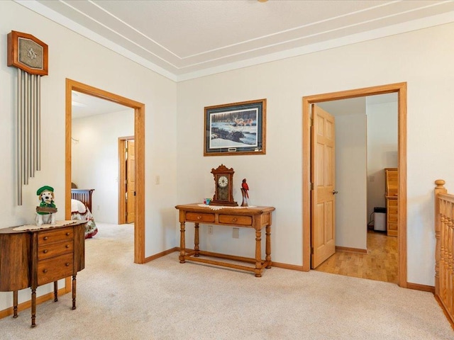 corridor with baseboards and light colored carpet