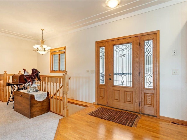 foyer with visible vents, wood finished floors, baseboards, and a chandelier