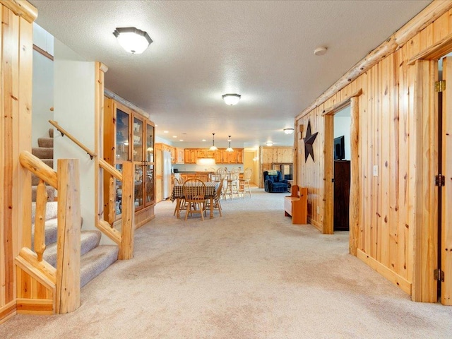 dining area featuring light colored carpet, stairs, and wood walls