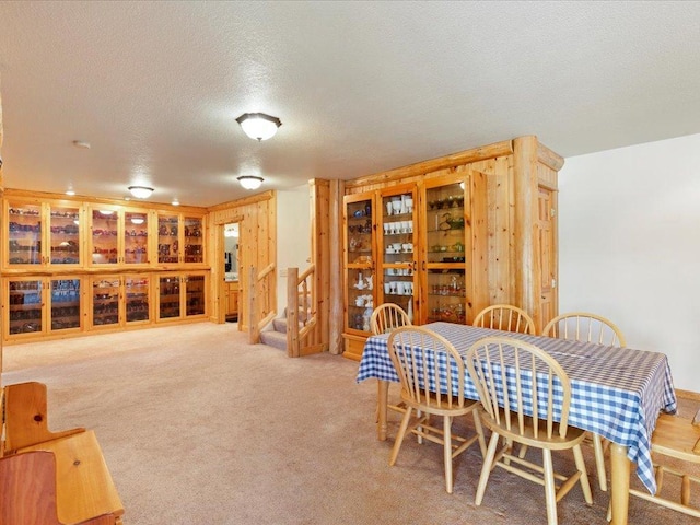 dining room featuring carpet floors, a textured ceiling, and stairs