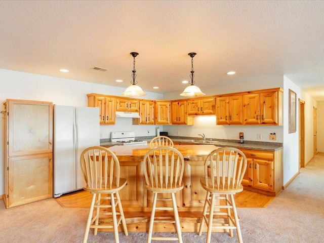 kitchen with white appliances, visible vents, a kitchen island, a sink, and decorative light fixtures