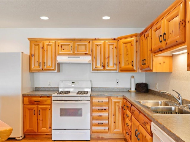 kitchen featuring under cabinet range hood, light wood-type flooring, recessed lighting, white appliances, and a sink