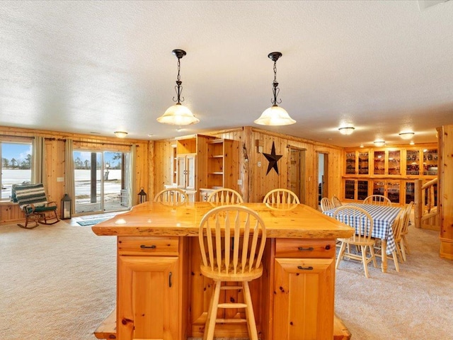 kitchen featuring a kitchen island, decorative light fixtures, butcher block countertops, light colored carpet, and a textured ceiling