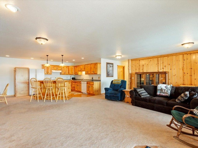 living area featuring recessed lighting, light carpet, a textured ceiling, and wooden walls