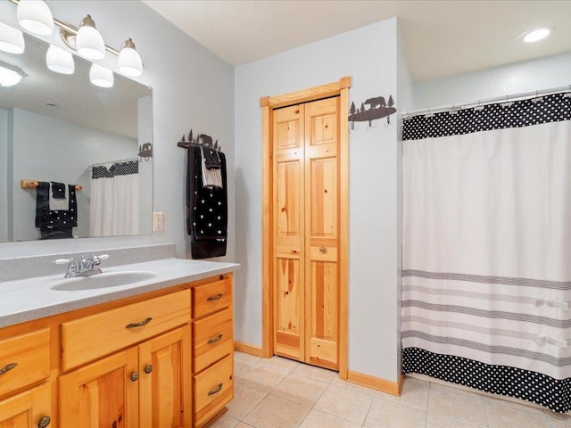 bathroom with curtained shower, baseboards, vanity, and tile patterned flooring