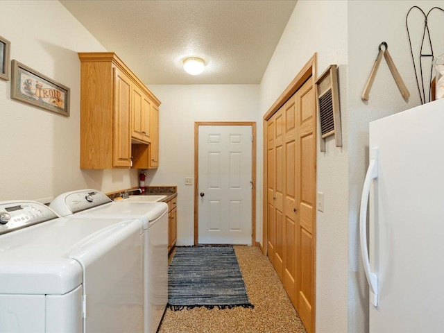 laundry room featuring washer and dryer, a sink, cabinet space, and a textured ceiling