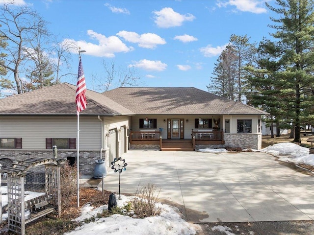 view of front facade with covered porch, concrete driveway, a garage, and roof with shingles