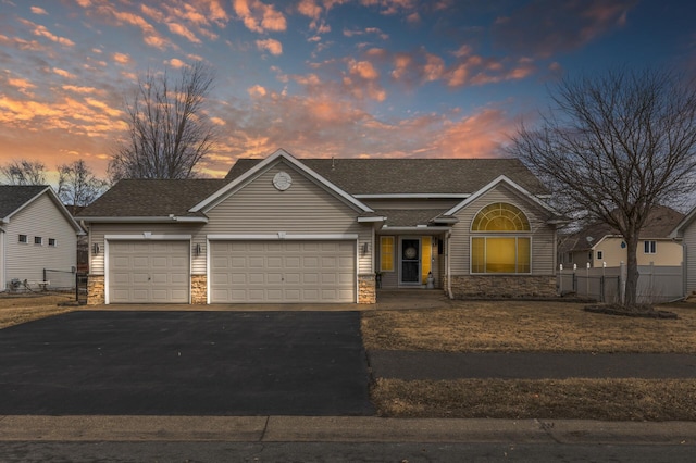 view of front of home with roof with shingles, an attached garage, fence, stone siding, and driveway