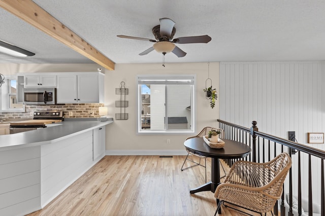 kitchen featuring tasteful backsplash, stainless steel appliances, a textured ceiling, light wood-style floors, and beam ceiling