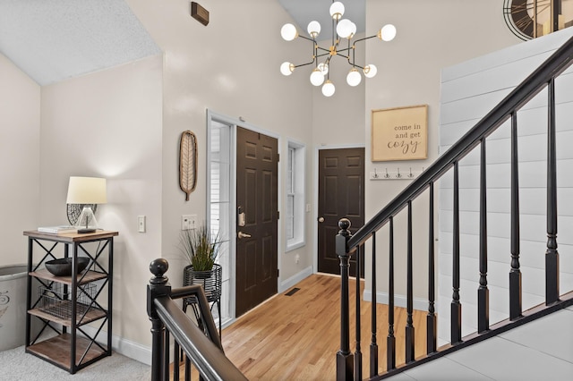 entryway with a high ceiling, stairs, baseboards, and a notable chandelier