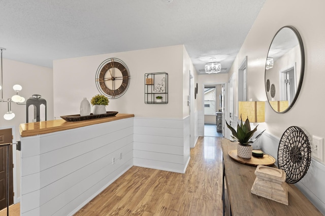 hallway with light wood finished floors and a textured ceiling