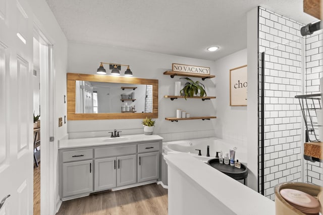 bathroom with a shower, a garden tub, a textured ceiling, vanity, and wood finished floors