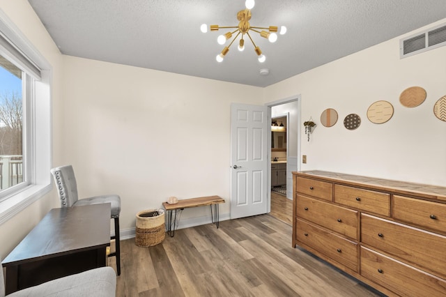 interior space with visible vents, baseboards, light wood-style flooring, an inviting chandelier, and a textured ceiling